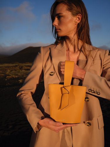 bolso tipo bucket de piel amarillo hecho a mano con detalle de nudo, asa superior y bandolera